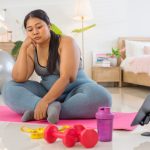 A woman sitting on an exercise mat and does not want to exercise.
