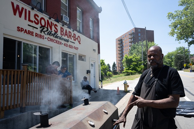 رجل يشير إلى مدخن كبير بينما يتكئ رواد المطعم الجائعون على حاجز أثناء انتظار طلبهم