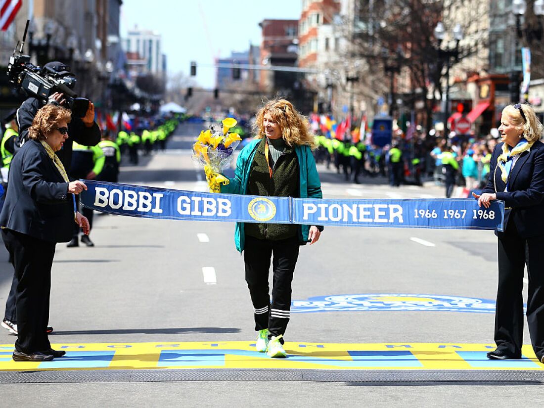 بوبي جيب تعبر خط النهاية خلال ماراثون بوسطن في عام 2016. وهي تحمل باقة من الزهور الصفراء.  إنها تعبر شريط خط النهاية الذي يقول: 