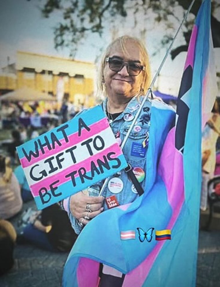 أندريا مونتانيز تحمل لافتة كتب عليها: "يا لها من هدية أن تكون متحولًا" وعلم العابر